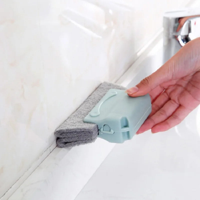 Mano usando esponja de limpieza gris con mango plástico para limpiar juntas en baño