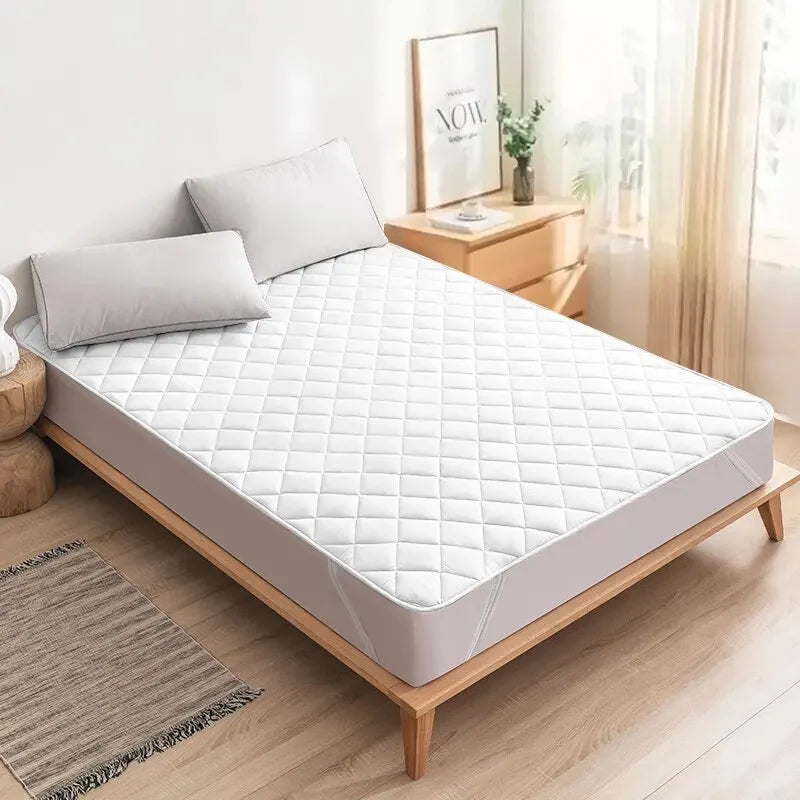 Protector de colchón blanco acolchado en dormitorio moderno con luz natural y decoración minimalista