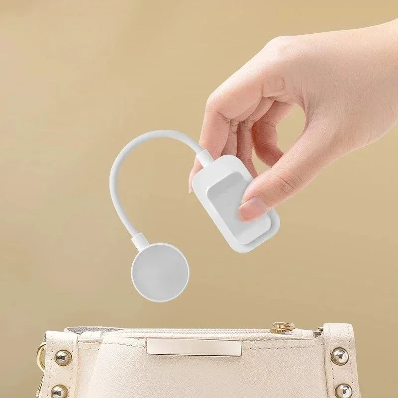Mano sosteniendo gadget blanco moderno de limpieza portátil cerca de bolso beige