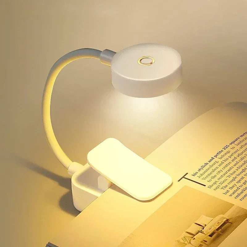 Lámpara LED blanca de clip para lectura, ideal para mesas y libros, luz cálida y moderna.