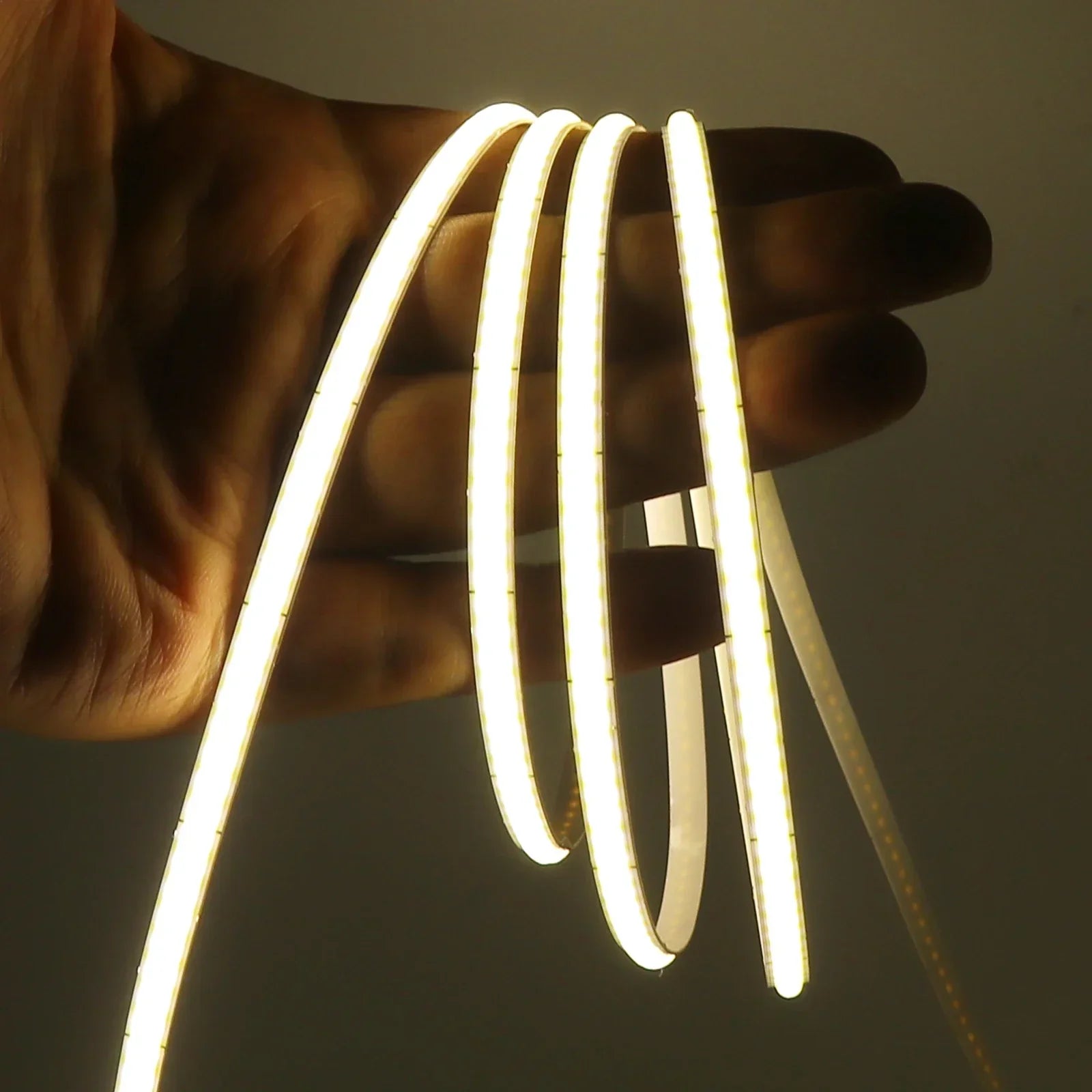 Tira de luces LED cálidas enrollada sobre una mano, ideal para iluminación decorativa de interiores.