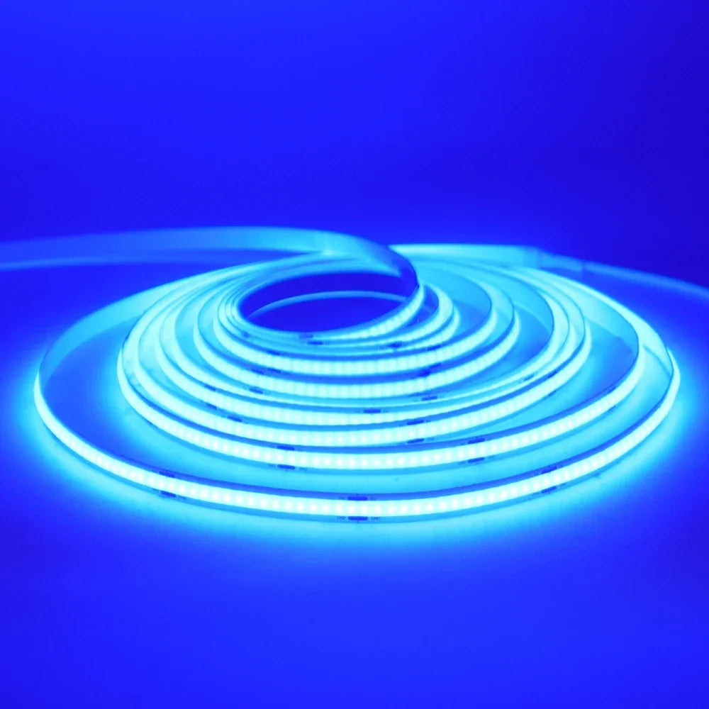 Tira de luces LED azul brillante enrollada sobre superficie blanca, ideal para iluminación decorativa.